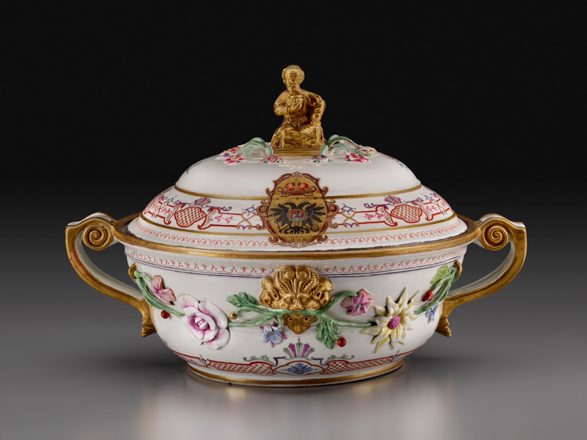photo of tureen decorated with flowers, with handles, and figure at top