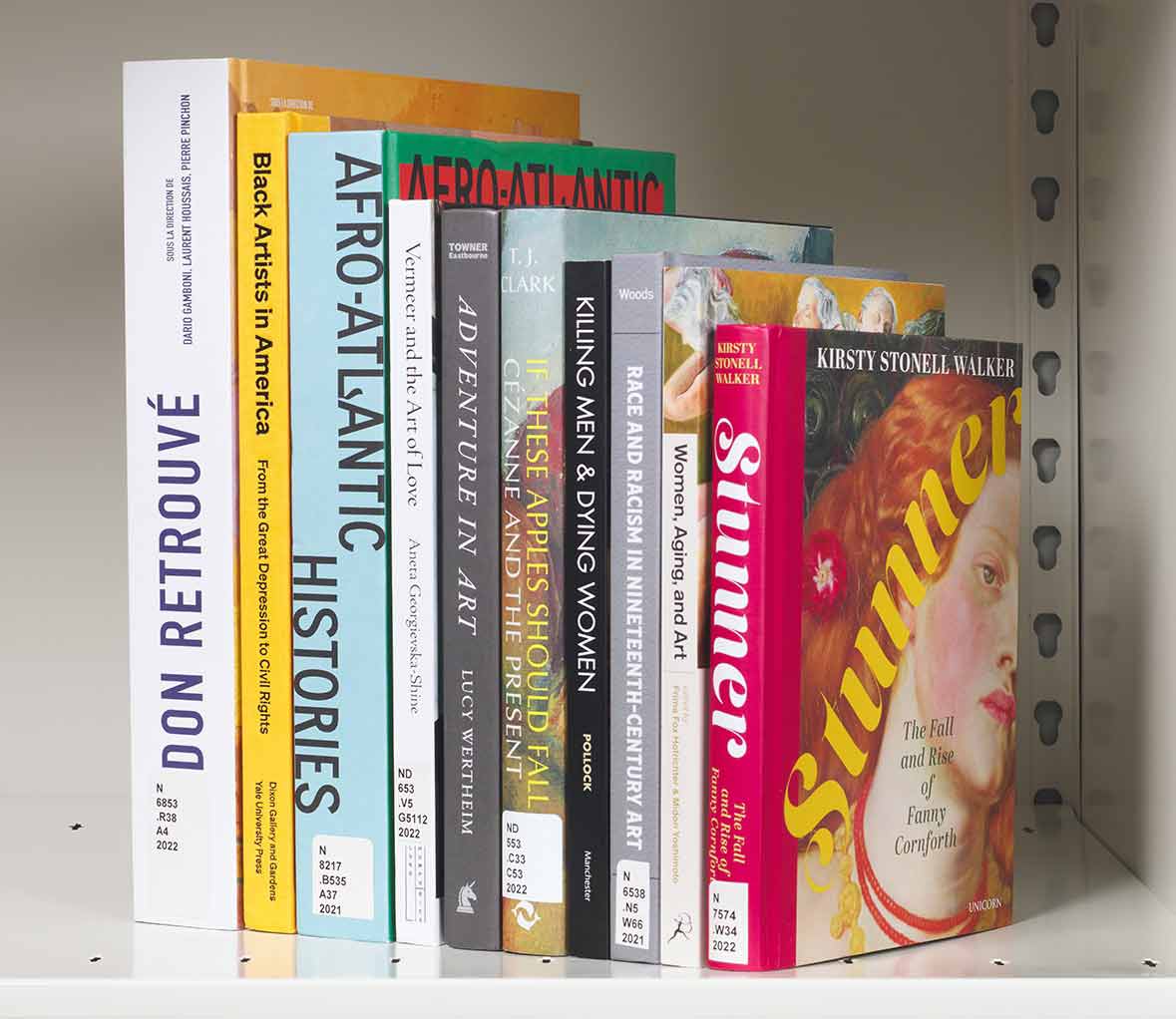 Vertical stack of ten colorful books on a white shelf