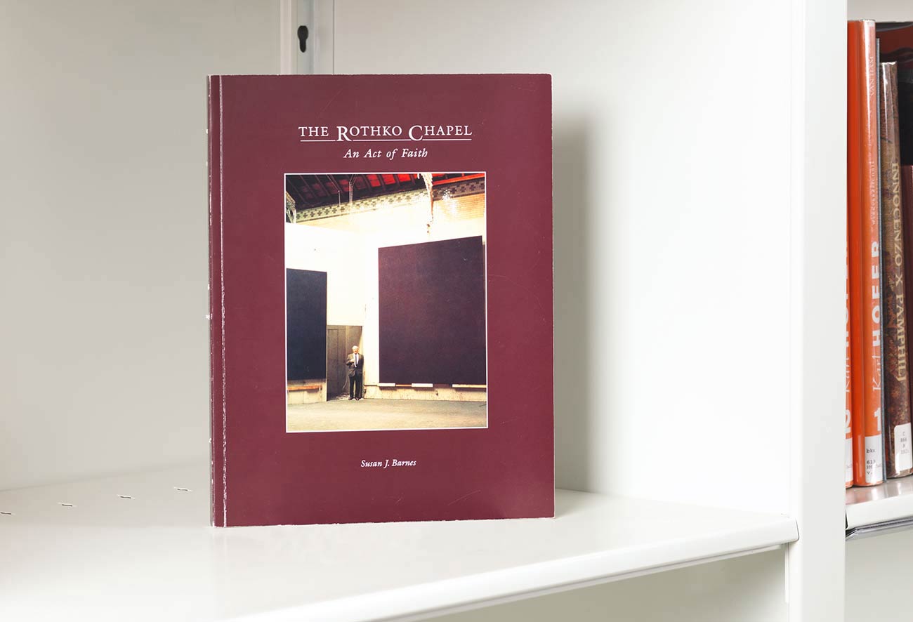 Book on a white shelf whose covers features a man standing near giant monochromatic canvases