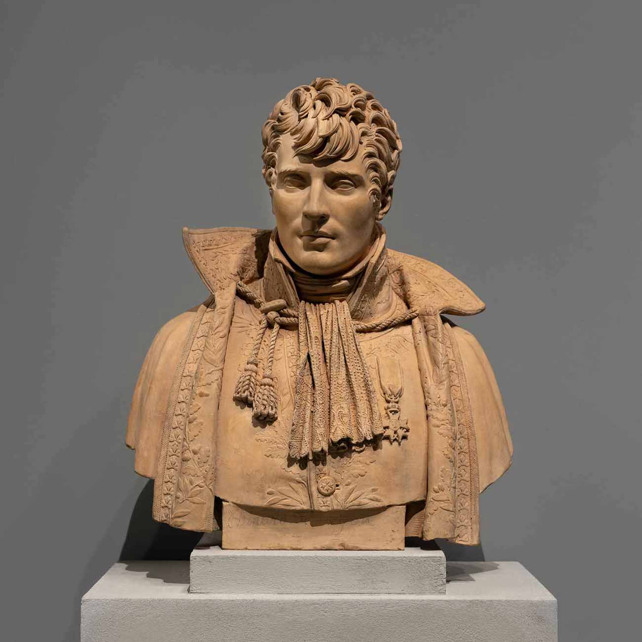 Terracotta bust of a young man with a wide lacy collar, an imperial medal, and elaborate curly hair