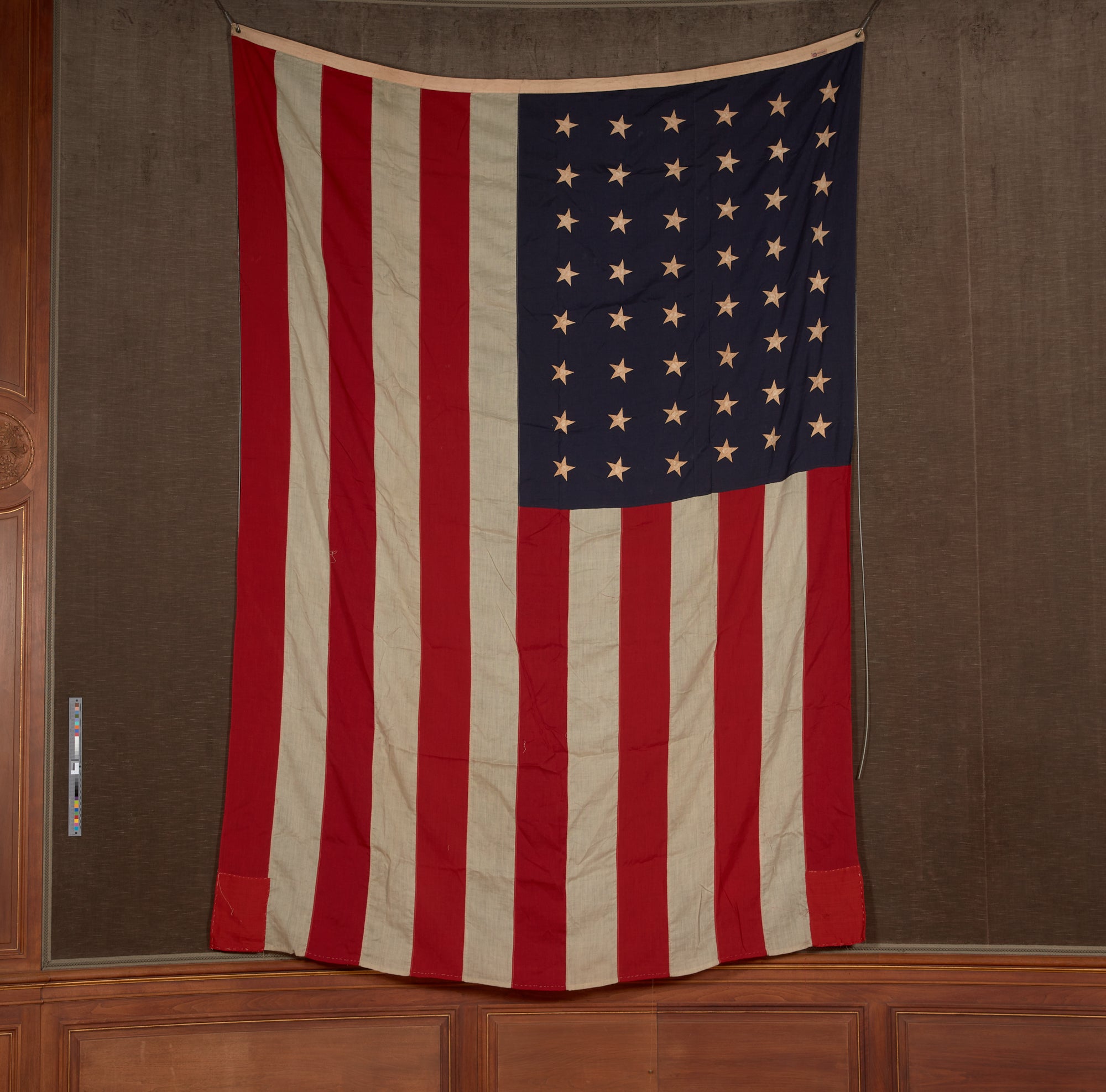 An American flag with 48 stars hanging vertically.