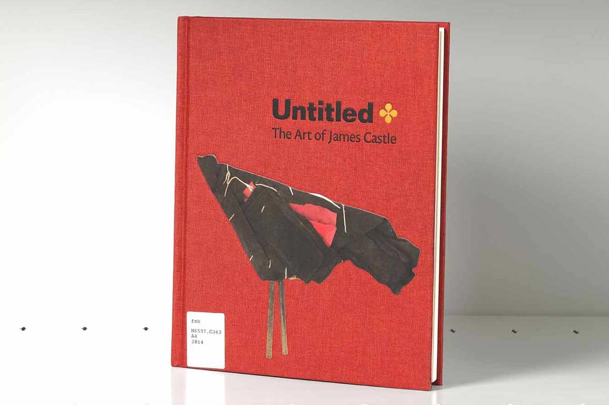 Book on a gray shelf whose red cover features an abstract artwork made of found black fabric