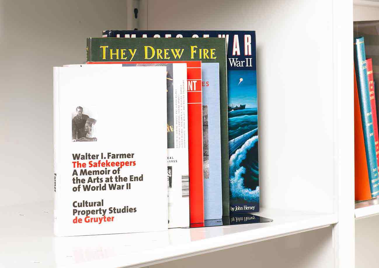 Six books about art and World War Two stacked on a white shelf