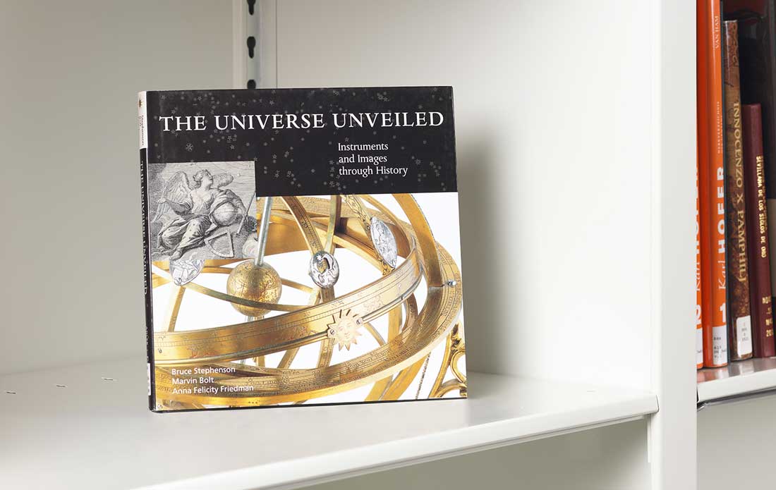 Book on a white shelf whose cover features details of metal astronomical instruments