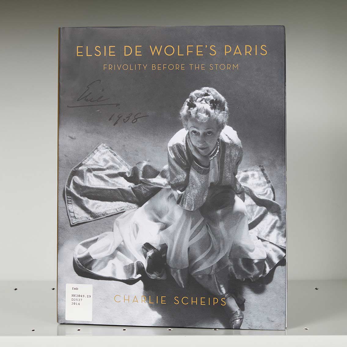 Book cover on a shelf featuring a photo of an elegant woman in a gown seated on the floor