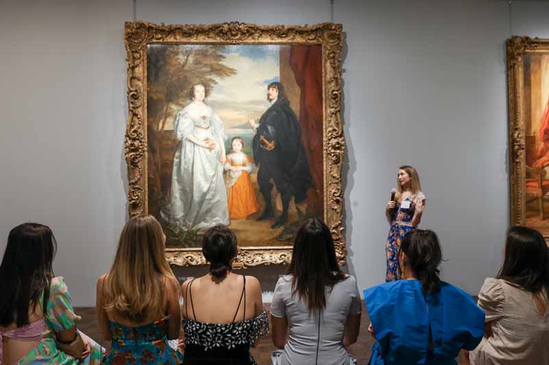 Museum visitors seated in front of painting at a gathering