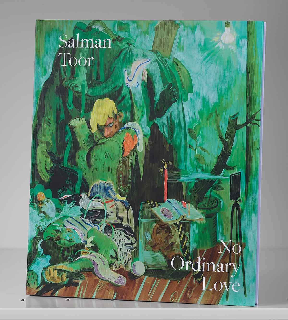 Book cover on a shelf featuring an artwork of a male figure surrounded by an assortment of objects in a green room