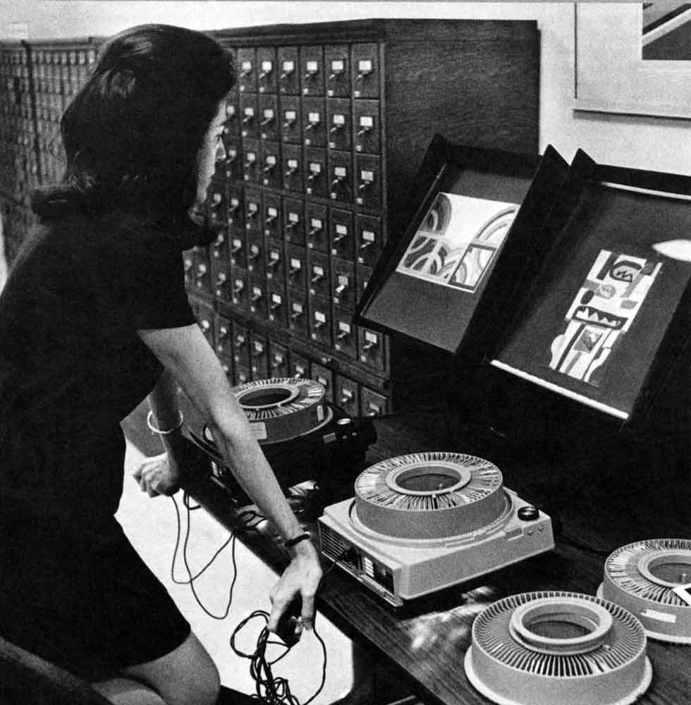 Black-and-white photograph of a woman looking at two screens.