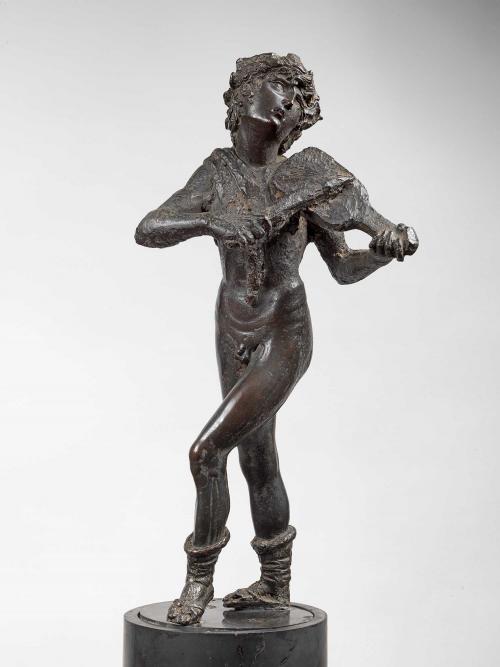 Bronze sculpture of a man playing an instrument that is propped on his shoulder.