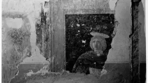 Corner of a room with a section of fresco depicting the head and shoulders of a young blond man.