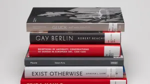 Stack of six books on LGBTQ+ art history with spines showing against a gray background