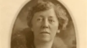 photo of Minerva Stone, with short hair, wearing long necklace and fur collar