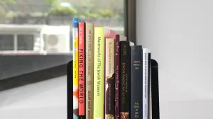 Stack of nine books on a black cart in front of a window