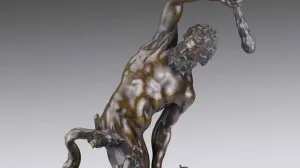 sculpture of nude man with club on top of monster