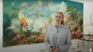 video still of woman standing in front of mural