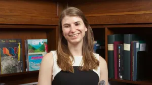 Woman in a black-and-white dress posing and smiling in front of bookshelves