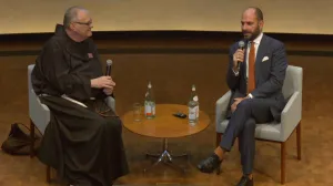 video still of conversation betweem two men on stage