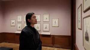 video still of person looking at prints in gallery