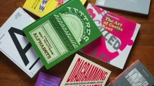 Stack of books with bold, vibrant covers strewn on a wooden desk