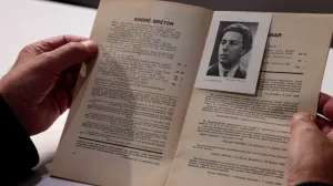 video still of hands holding booklet open with photograph of man included