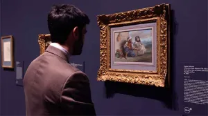 man standing in gallery looking at painting closely