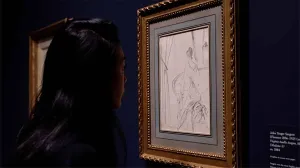 video still of Aimee Ng looking at drawing of woman closely