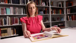 video thumbnail of woman looking at open book in library
