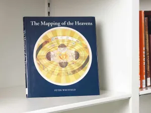 Book on a white shelf whose cover features a large yellow celestial map