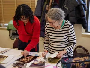 Museum educator with short curly hair looking at collages with an older woman in a striped shirt