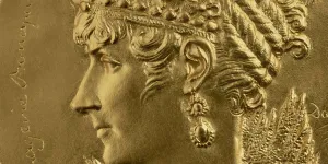 closeup of medal with woman's face in profile, her hair styled