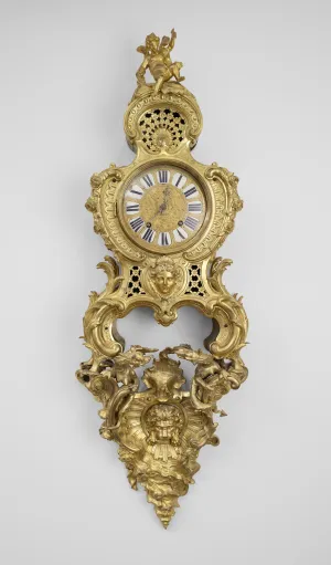 ornate gold four-legged clock standing on a wall bracket with angel at top and lion's head at bottom