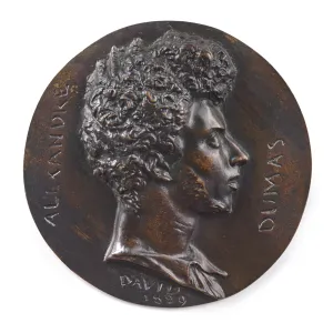 bronze of head of man in profile with curly hair atop circle of bronze with writing