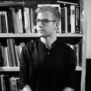 black and white photo of man standing in front of books