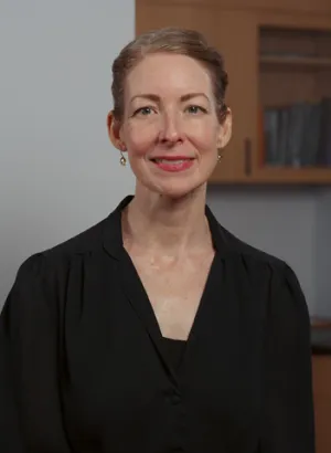 A woman in a black shirt in front of a cabinet
