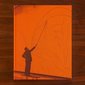 Orange book cover featuring a man standing on a bench drawing large figures on a wall with a long stick