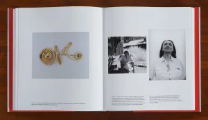 Book spread with photos of artist Georgia O'Keeffe and a metal brooch shaped in the letters "OK"