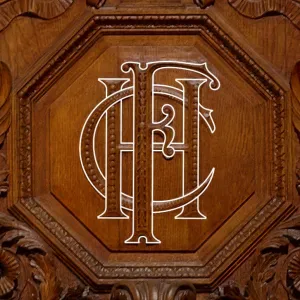 Monogram of letters H-C-F overlaid on a wood carving of the monogram