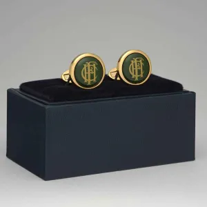 green faced cufflinks with monogram HCF sitting on top of open box