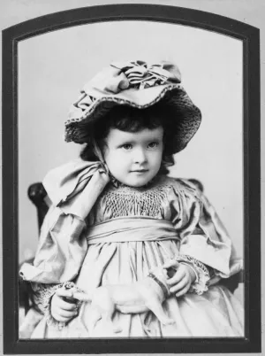 black and white photograph of young martha frick seated with bonnet and dress holding toy dog