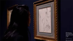 video still of Aimee Ng looking at drawing of woman closely